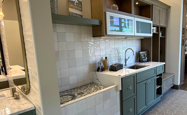 A modern pet grooming station with a sink, custom cabinets, and a tiled backsplash, featuring a framed picture of a dog.